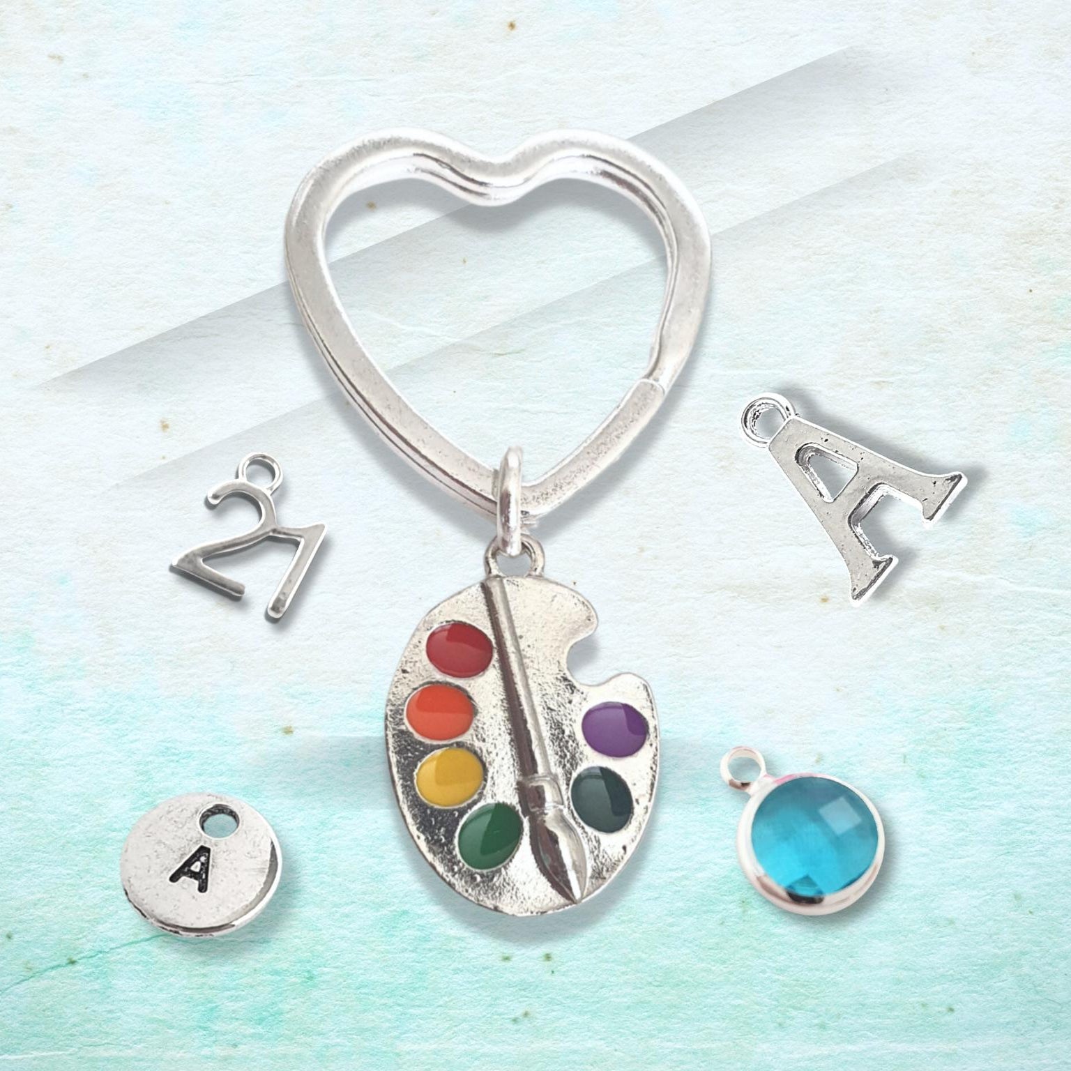 Silver keychain with heart-shaped design and various charms on a light blue background