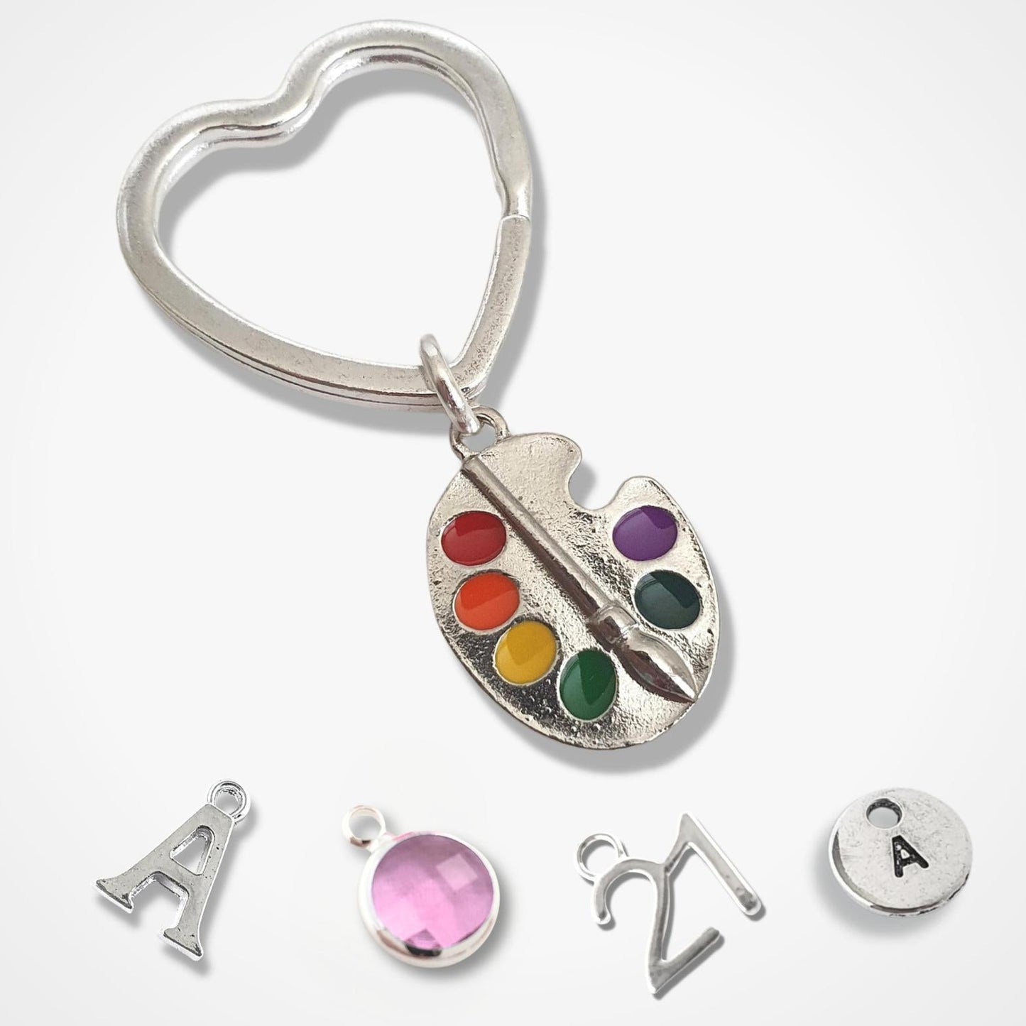 Silver keychain with a paint palette charm and additional charms on a white background
