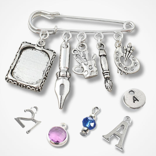 Silver brooch with various art charms on a white background
