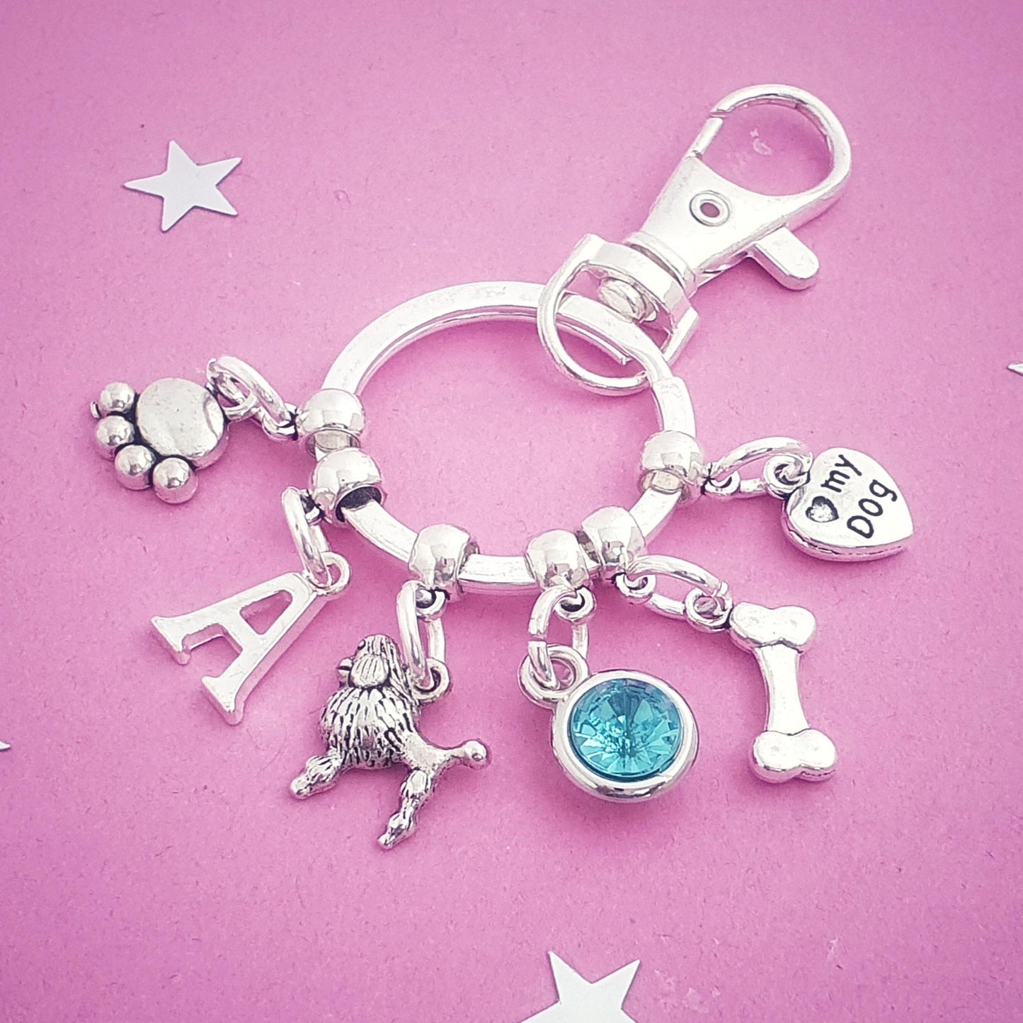 Silver keychain with various charms on a pink background