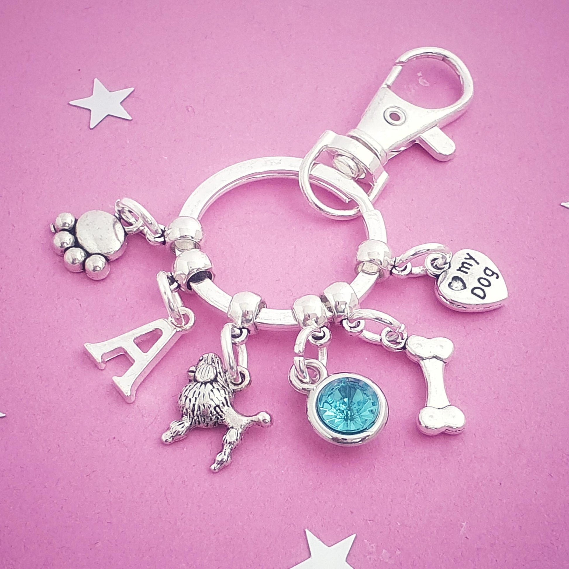Silver keychain with various charms on a pink background