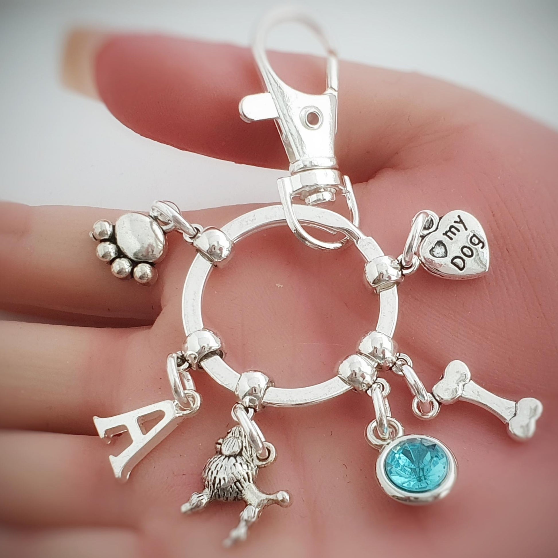 Silver keychain with various dog charms held in a hand