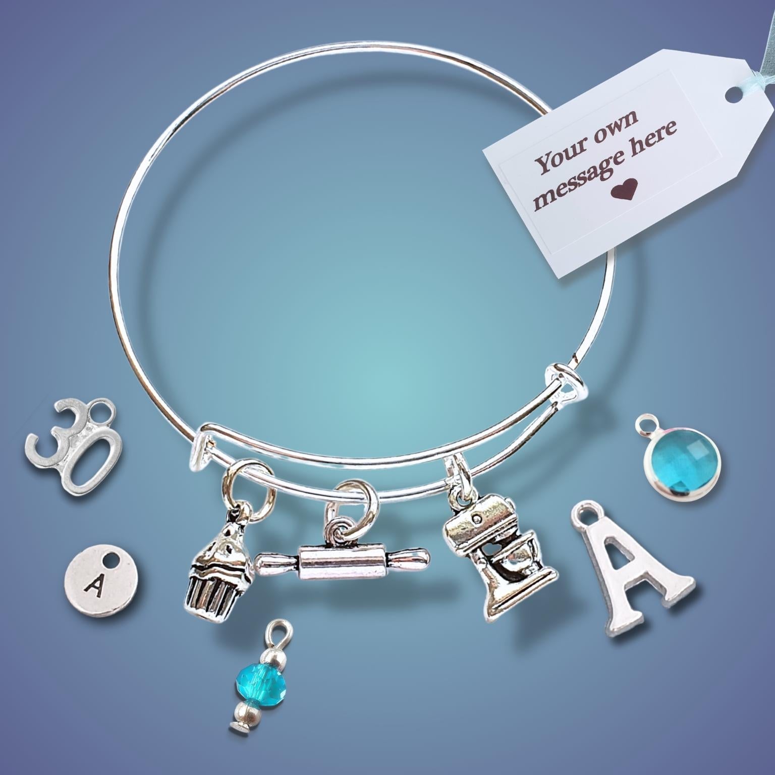 A silver bangle bracelet with multiple charms, including letters and small decorative icons, shown on a blue gradient background with a white gift tag that reads 'Your own message here'.