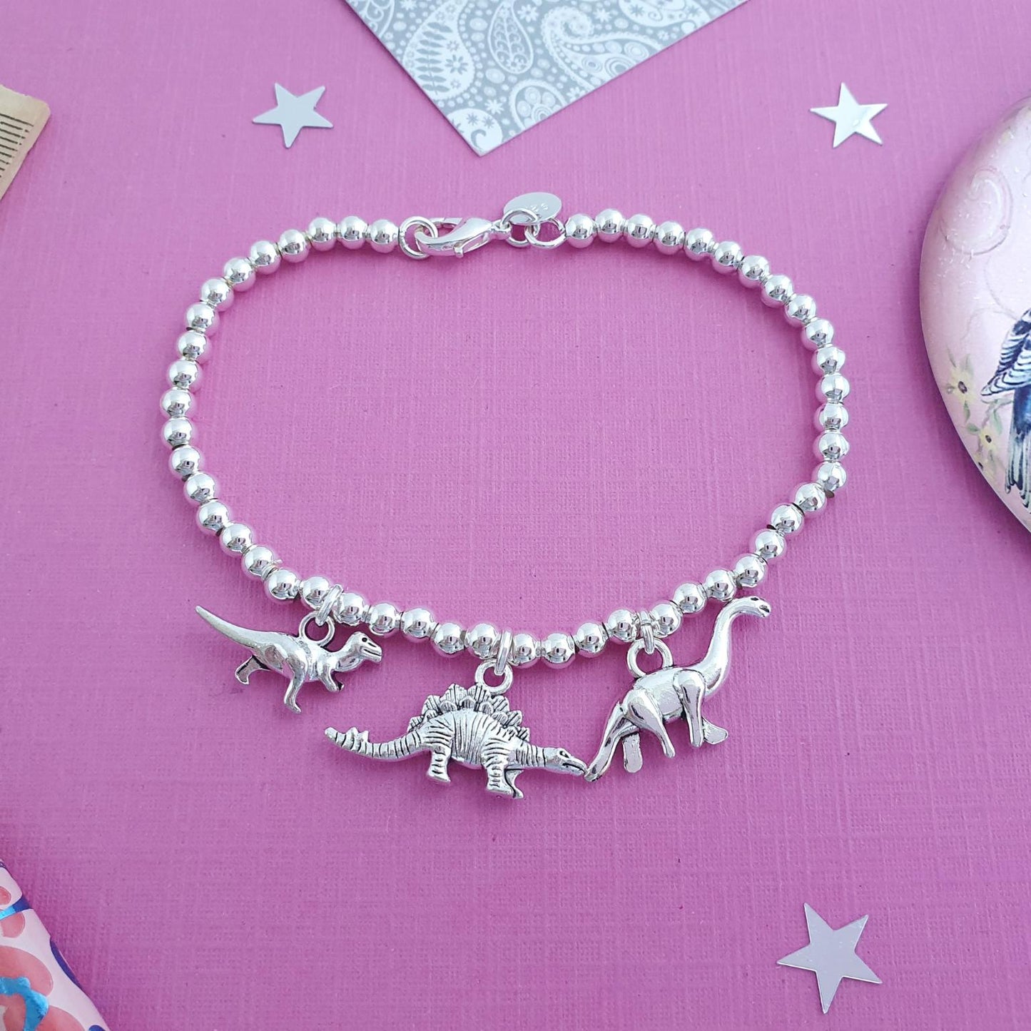 Bracelet with dinosaur charms on a pink background