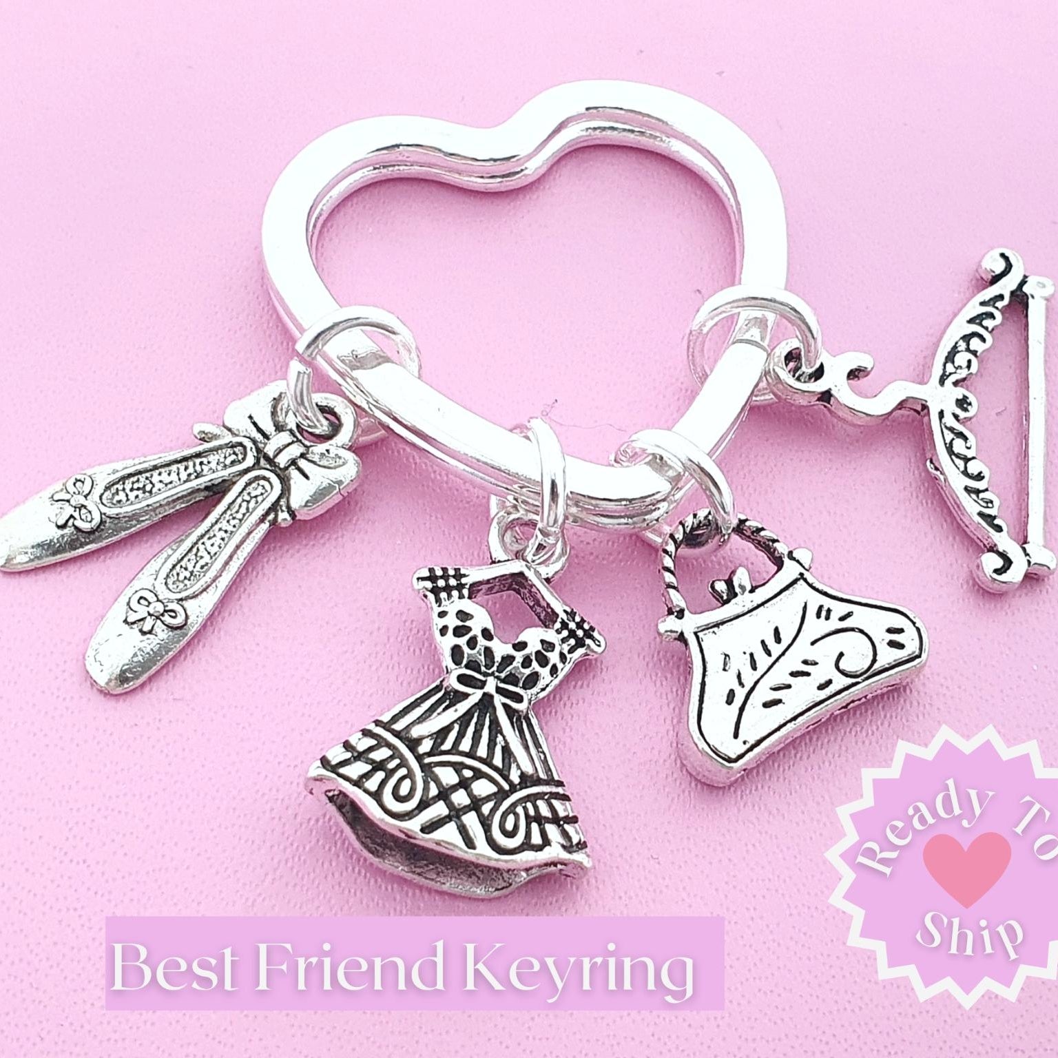 A silver-toned heart-shaped keyring charm set featuring charms shaped like a dress, a handbag, a coat hanger, and ballet slippers, displayed on a pink background with 'Best Friend Keyring' and a 'Ready To Ship' badge.