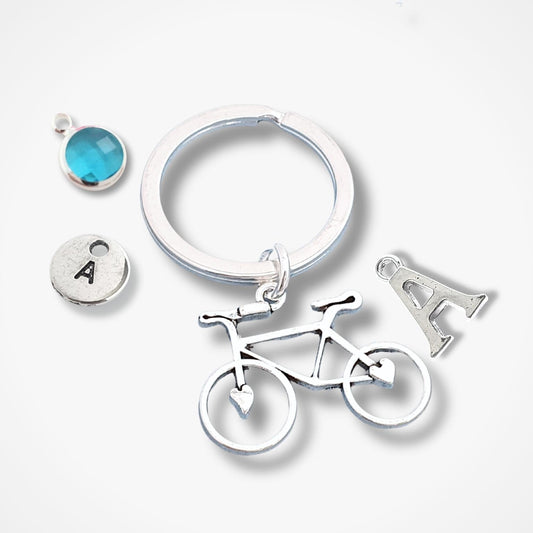 Silver keychain with bicycle, letter 'A', and round charm on a white background