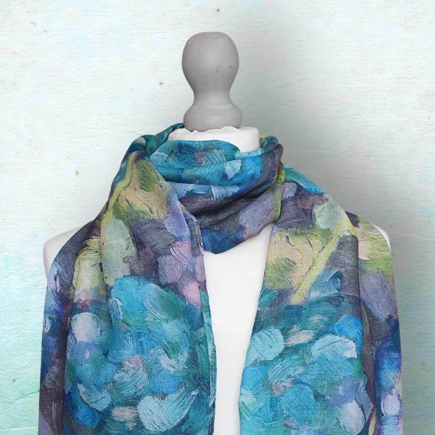Mannequin wearing a colorful scarf with a blue and green pattern on a light background