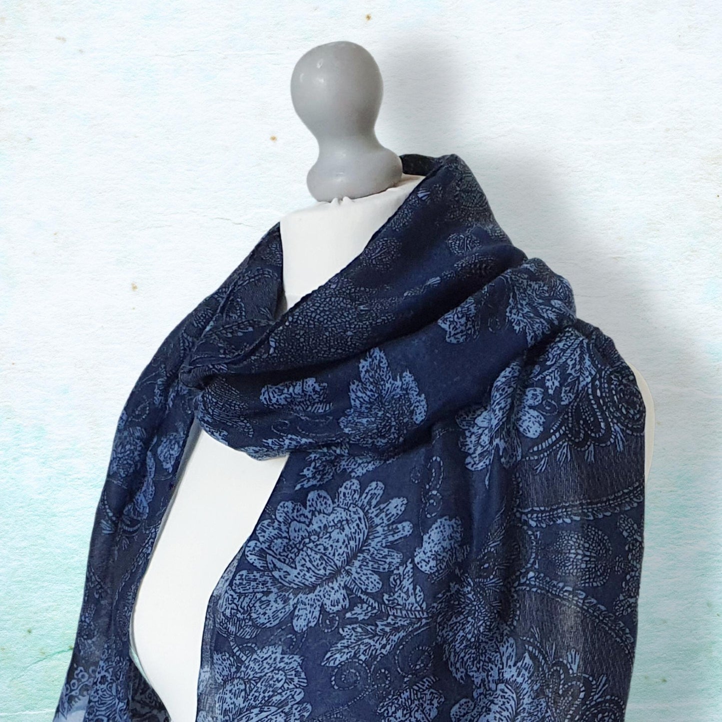 Navy blue patterned scarf on a mannequin against a light background