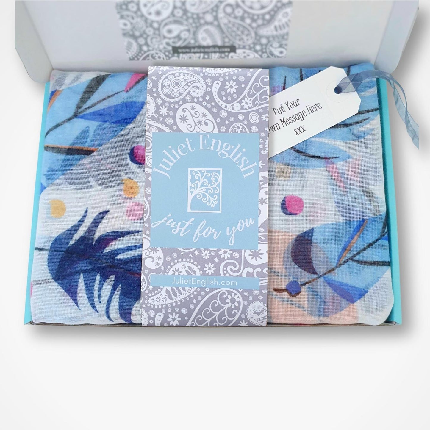 Packaged scarf with floral designs and a visible brand label on a white background