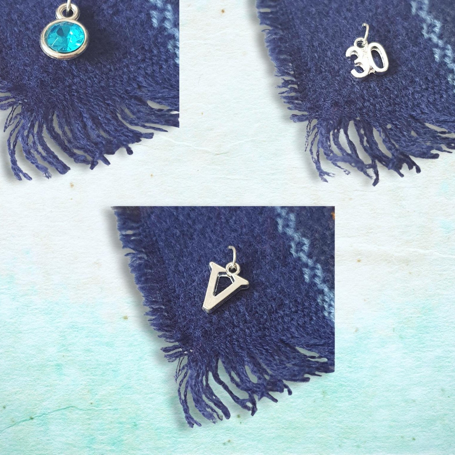 Three silver charms on a blue fabric background