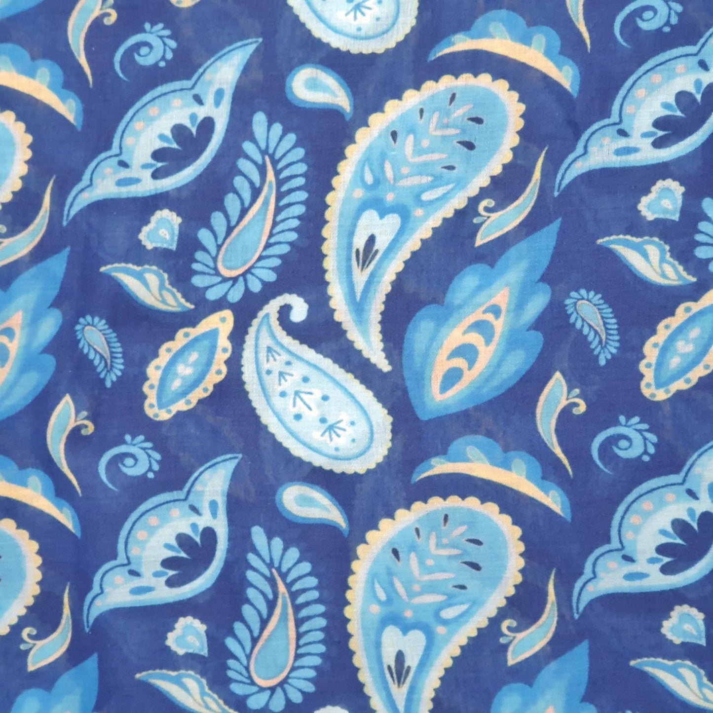 A close-up of a blue paisley patterned scarf fabric with light blue, white, and beige motifs.