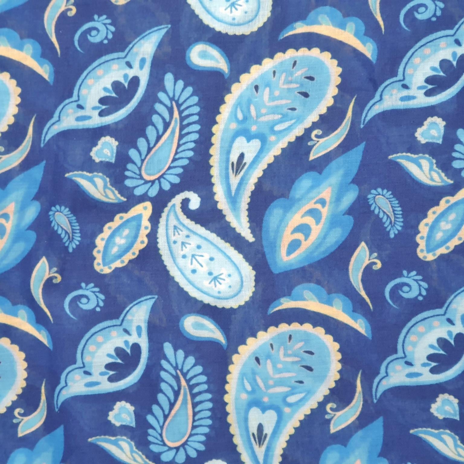 A close-up of a blue paisley patterned scarf fabric with light blue, white, and beige motifs.