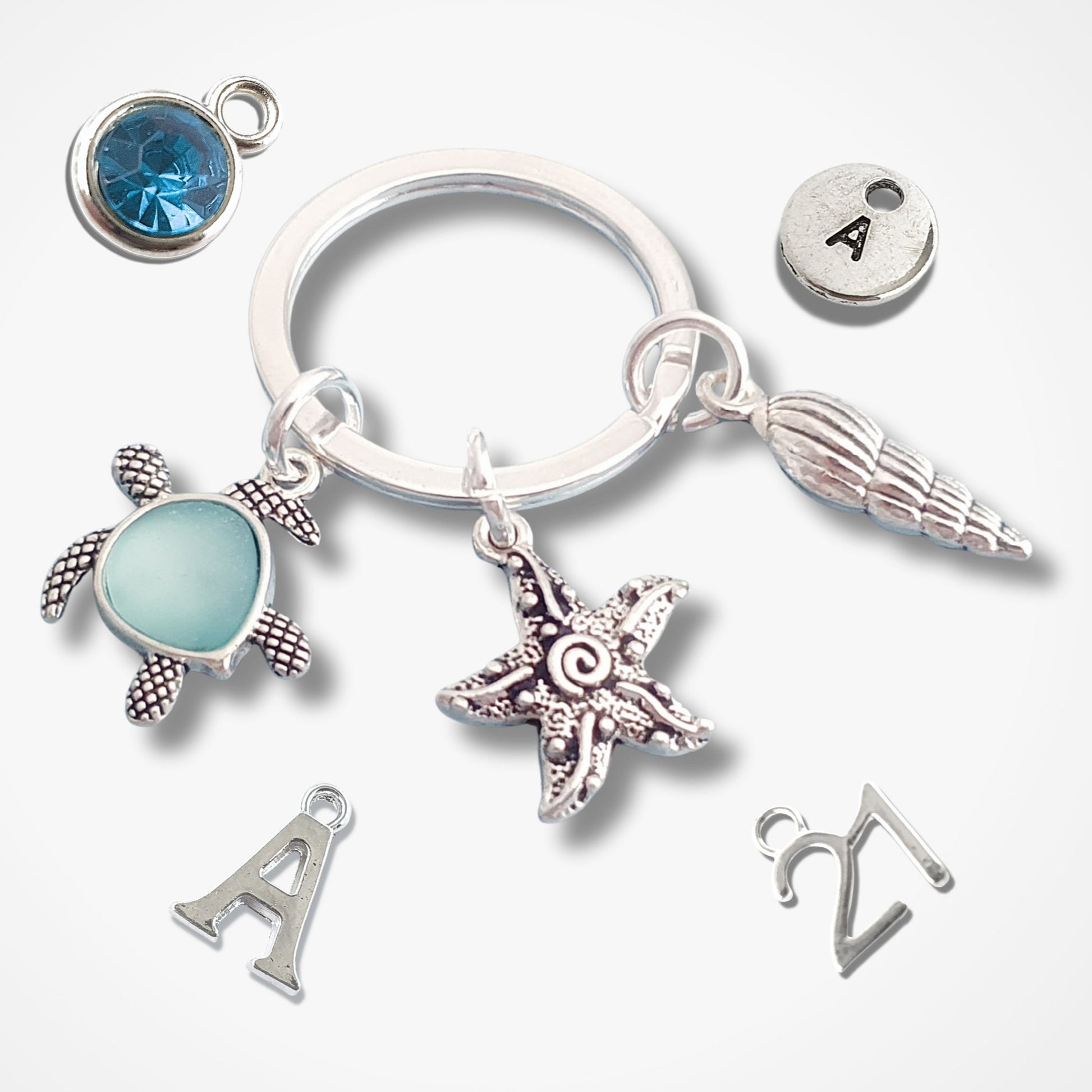 Silver keychain with various charms including a turtle, starfish, and shell on a white background.