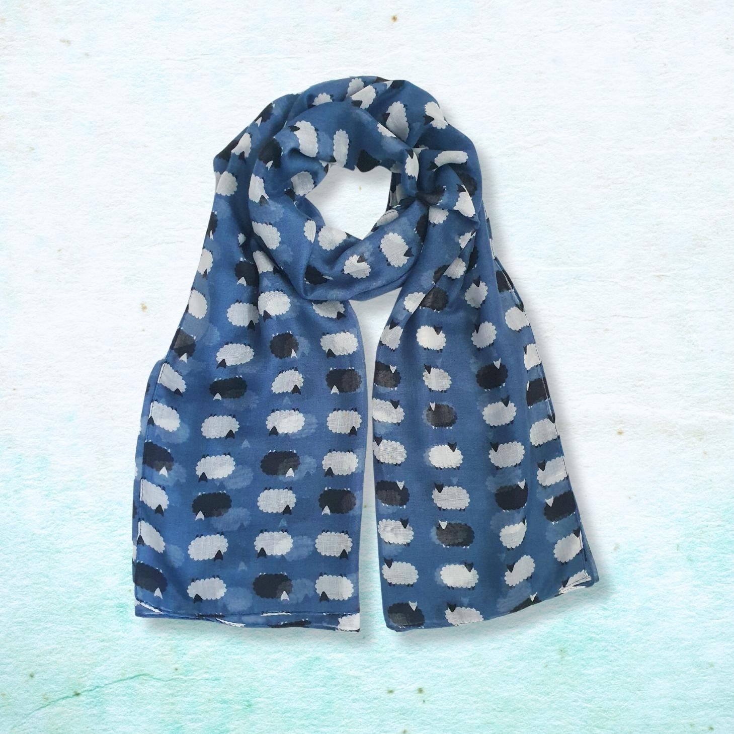 Blue scarf with black and white sheep pattern on a light blue textured background