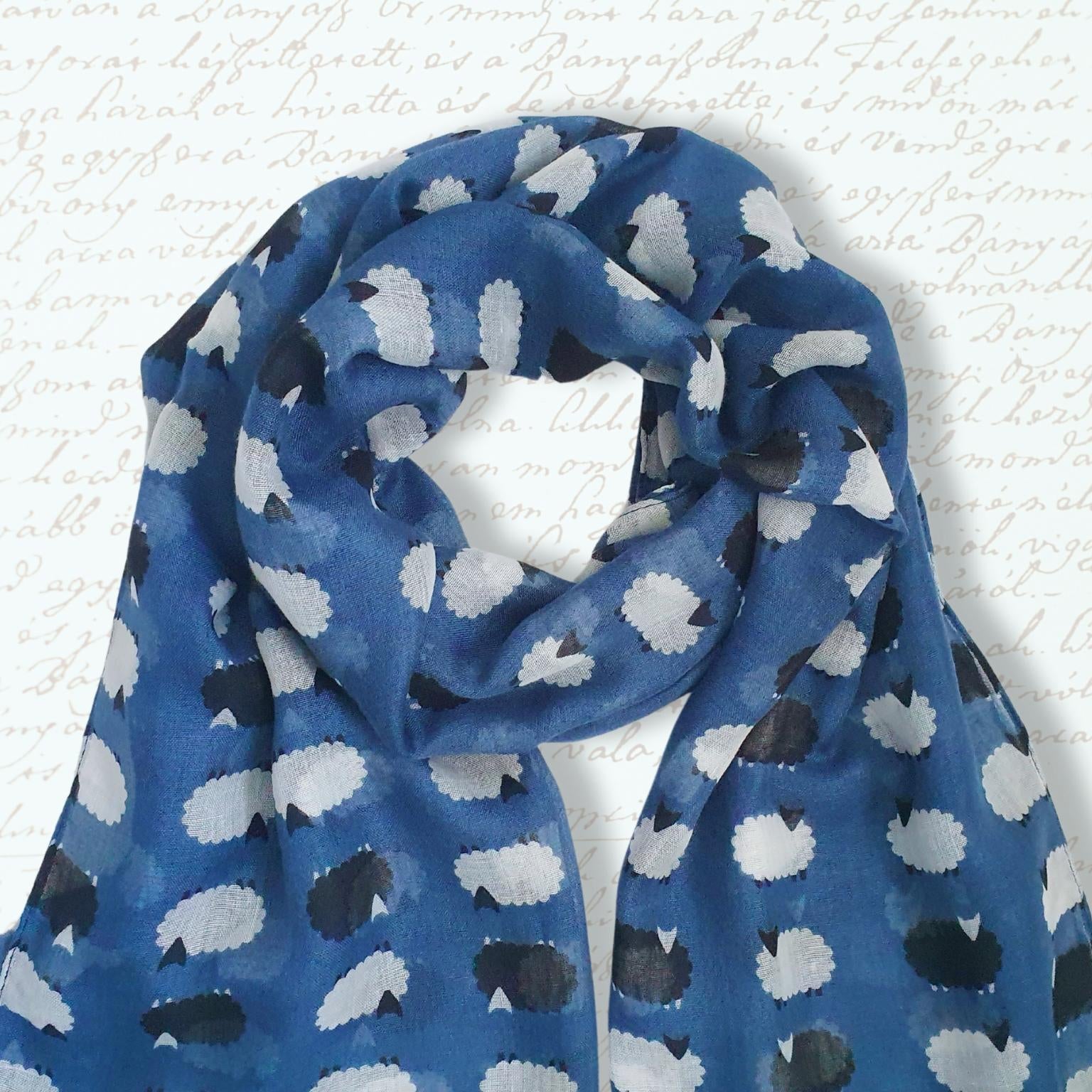 Blue scarf with white and black sheep pattern on a textured white background
