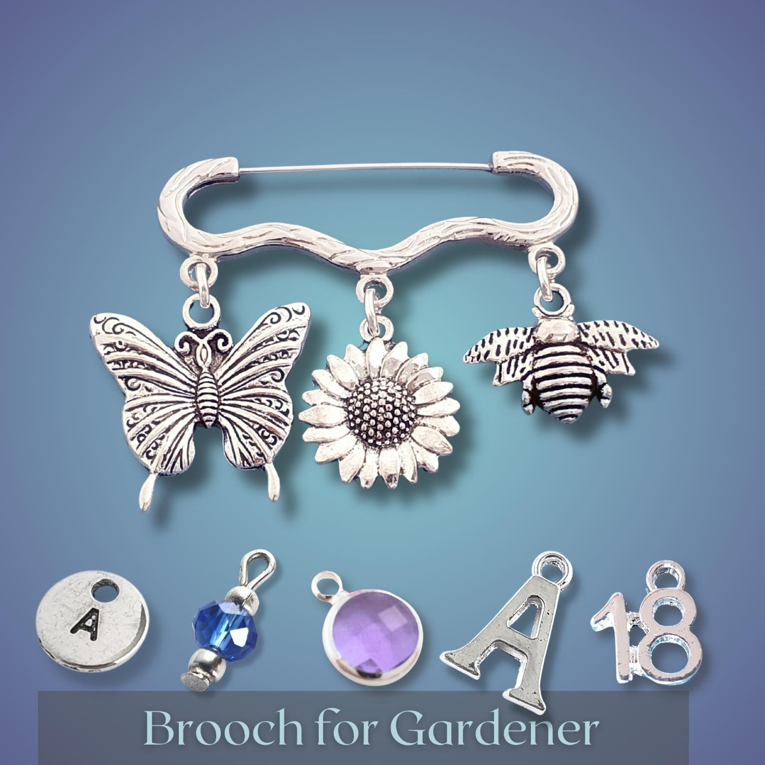 Silver brooch with butterfly, sunflower, and bee charms on a blue background
