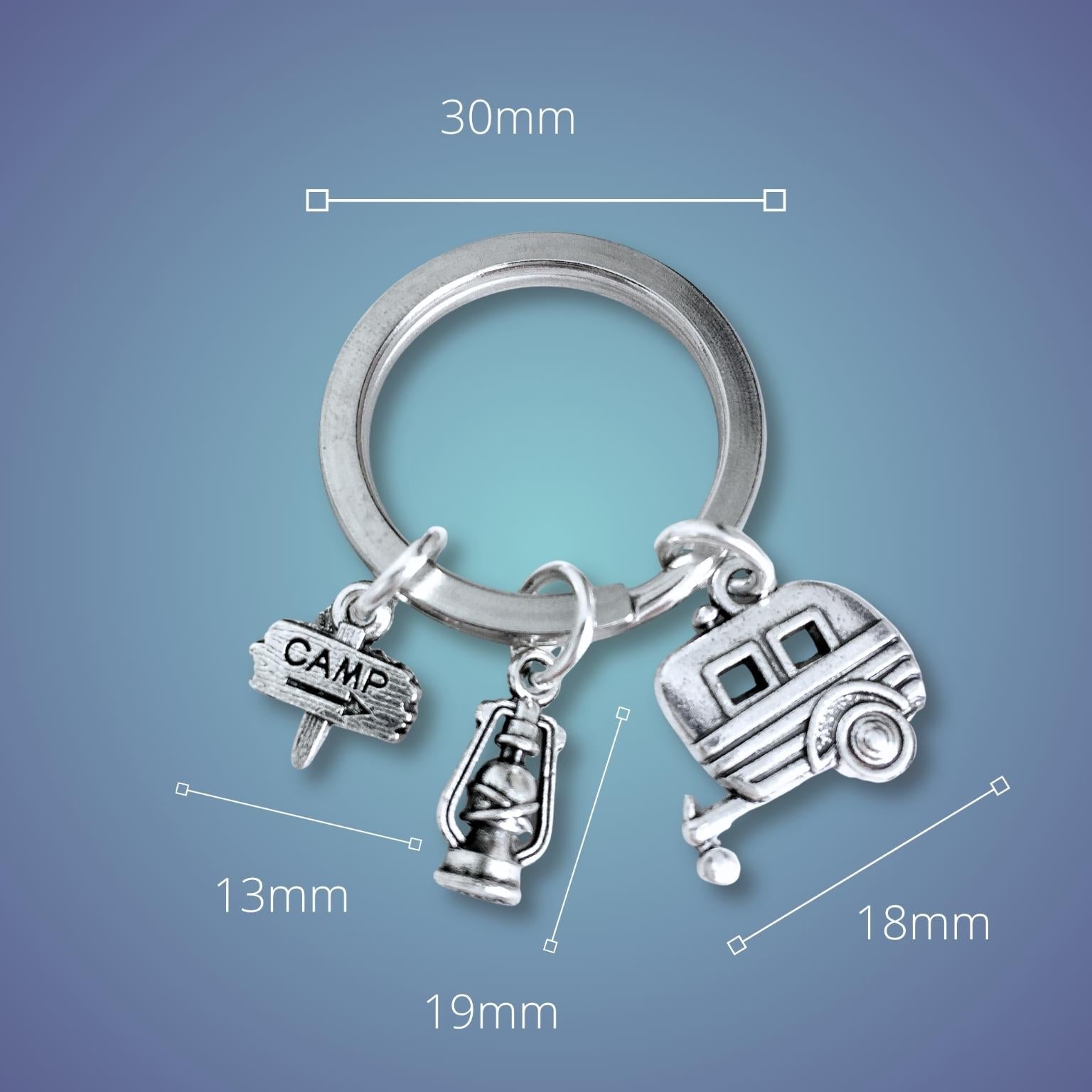 Silver keychain with camping-themed charms on a blue background