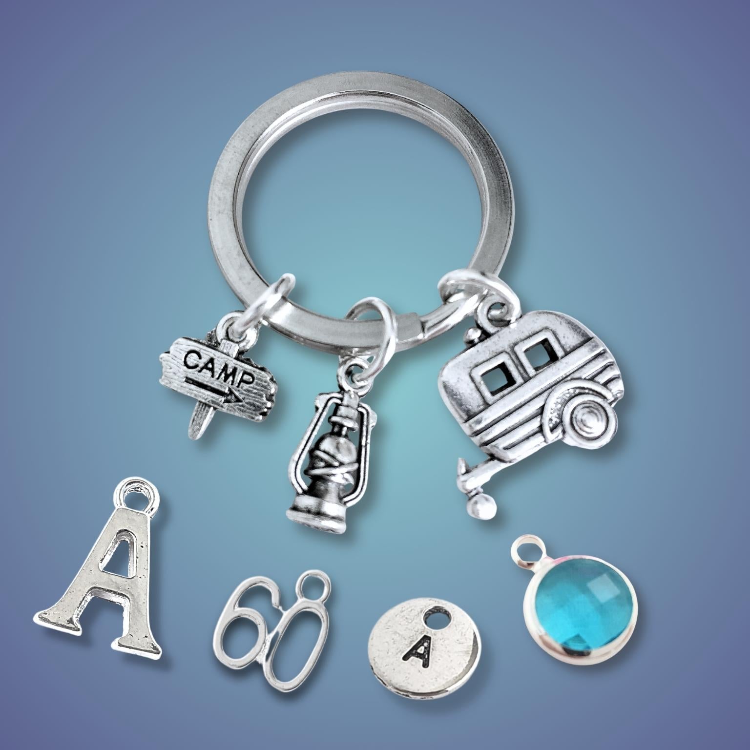 Silver keychain with caravan and camping charms on a blue gradient background
