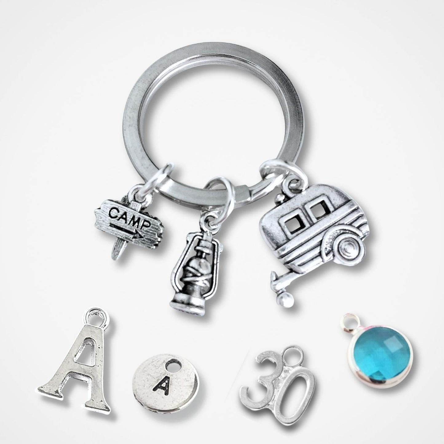 Silver keychain with caravan and camping charms on a white background