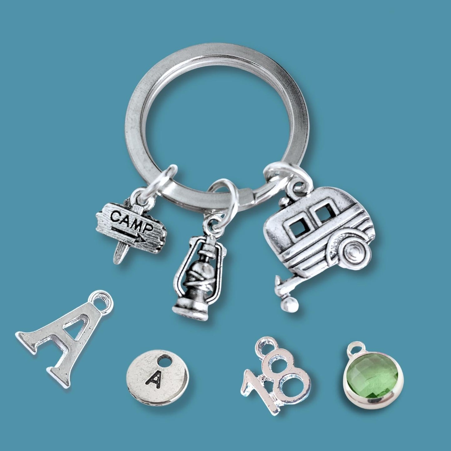Silver keychain with caravan and camping charms on a blue background