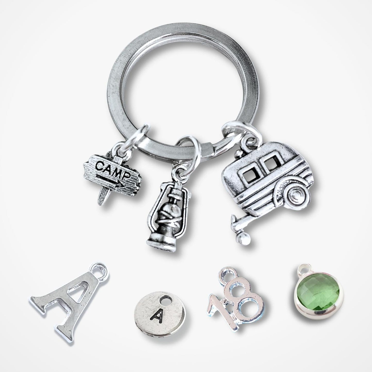 Silver keychain with caravan and camping charms on a white background