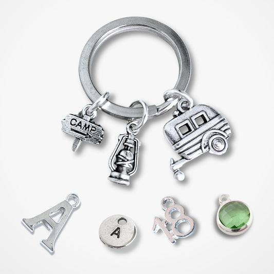 Silver keychain with caravan and camping charms on a white background