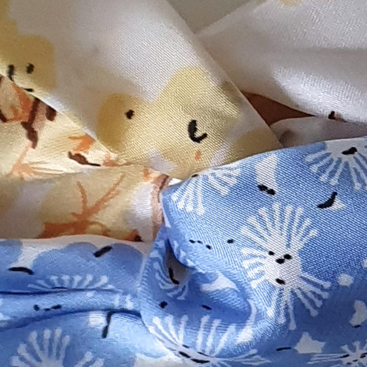 Close-up of patterned white fabric with light blue, yellow and brown floral details.