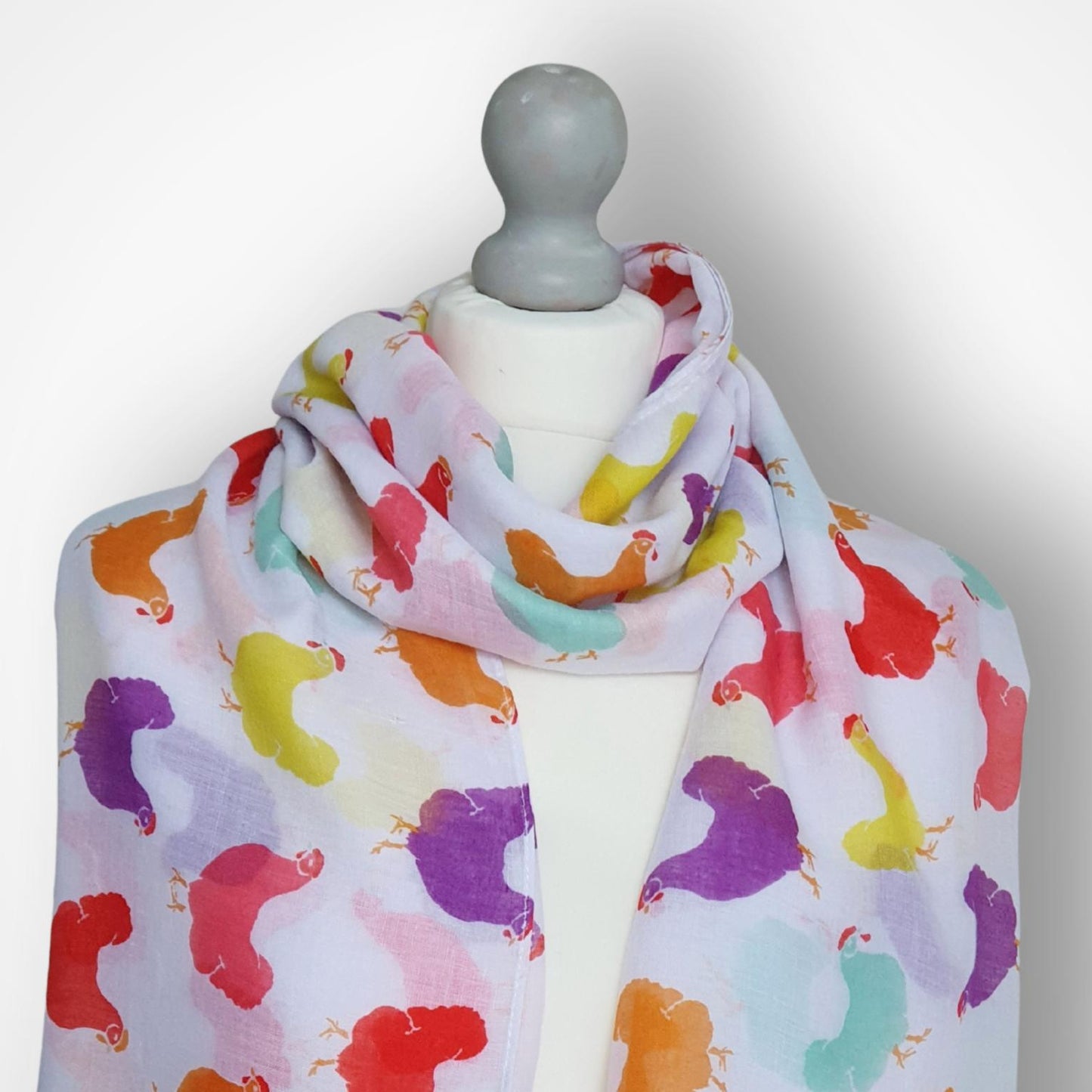 Colorful scarf with hen pattern on a mannequin against a white background