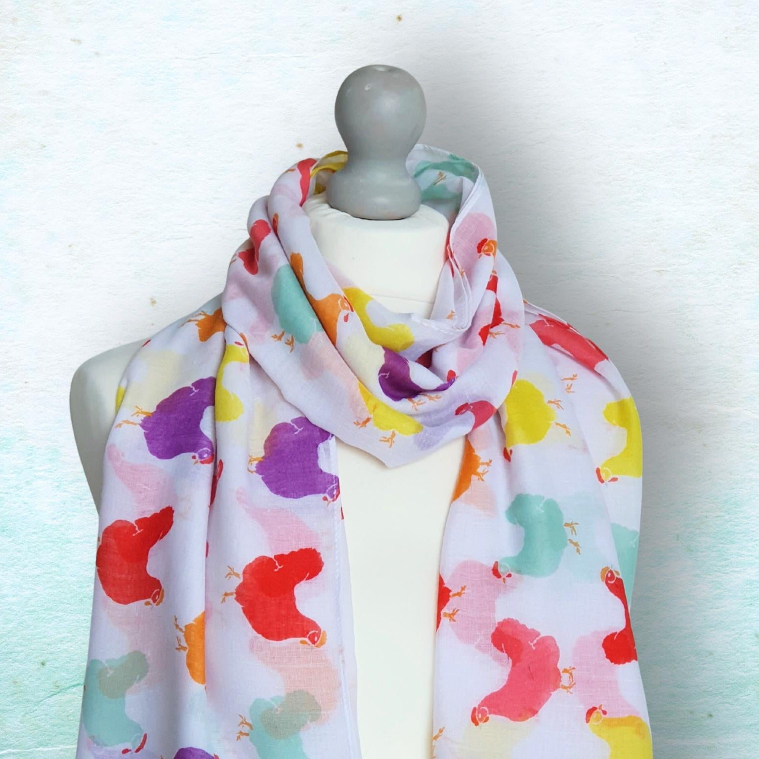 Colorful scarf with chickens patterns on a mannequin against a light background