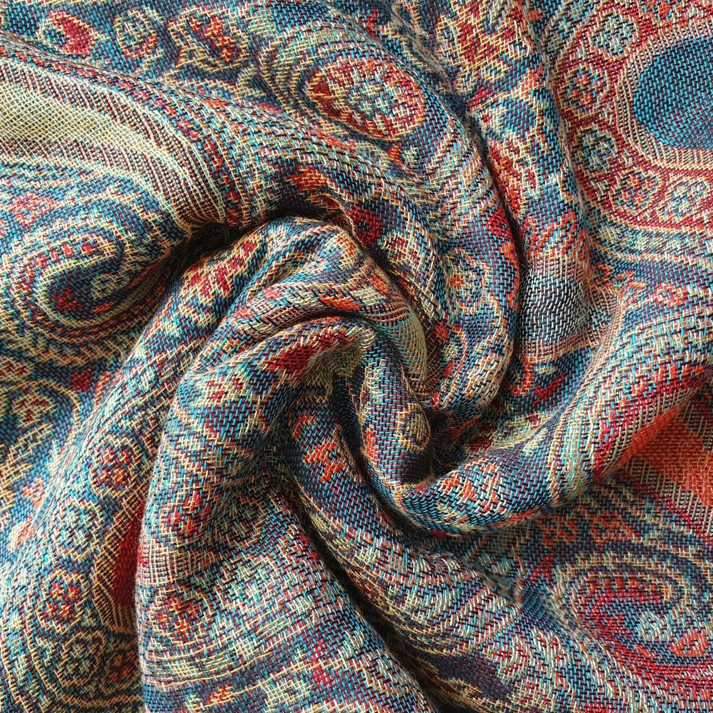A close-up of a paisley patterned fabric swirled in the center, showing a detailed woven design in blue, red, beige, and orange.