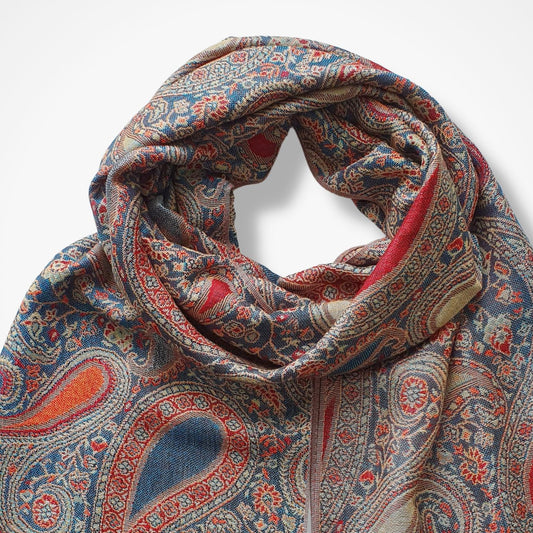 A woven scarf with an intricate paisley pattern in blue, red, orange, and beige, draped in a loop against a plain white background.
