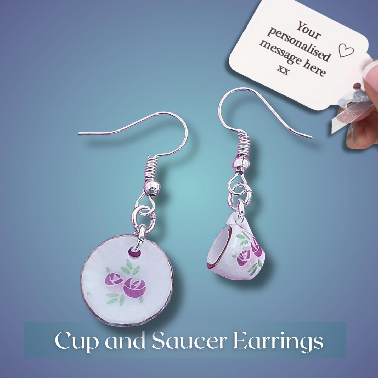 Cup and saucer earrings with a personalized message tag on a blue background