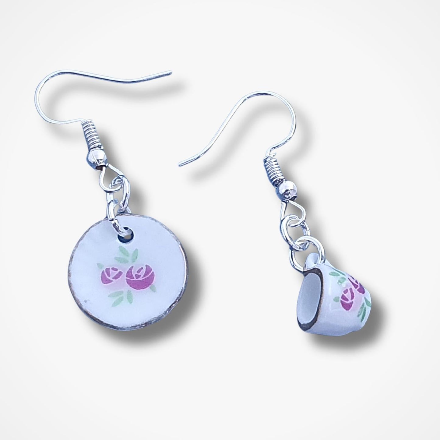 Pair of cup and saucer earrings with floral designs on a white background