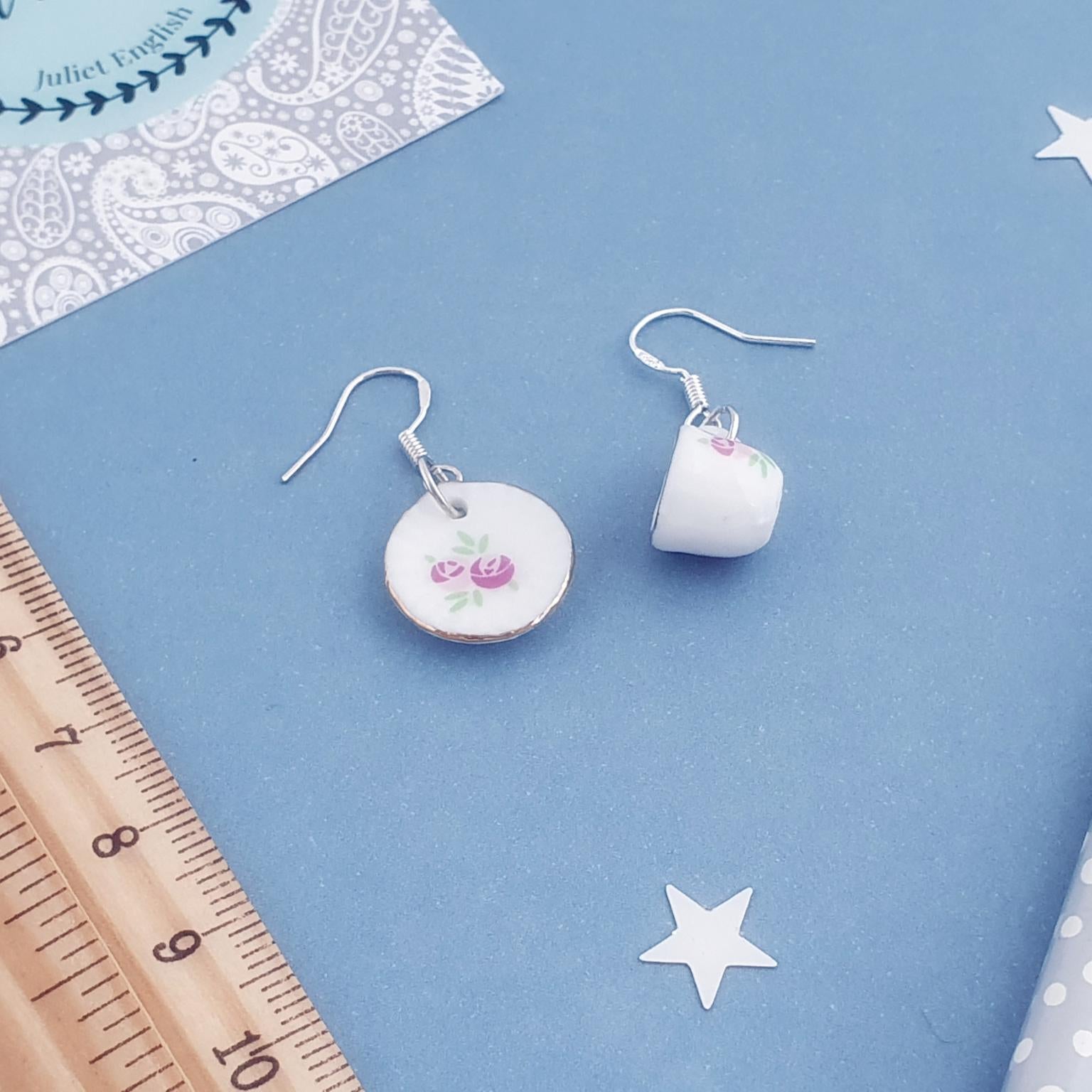 Teacup-shaped earrings on a blue background with stars and a ruler.