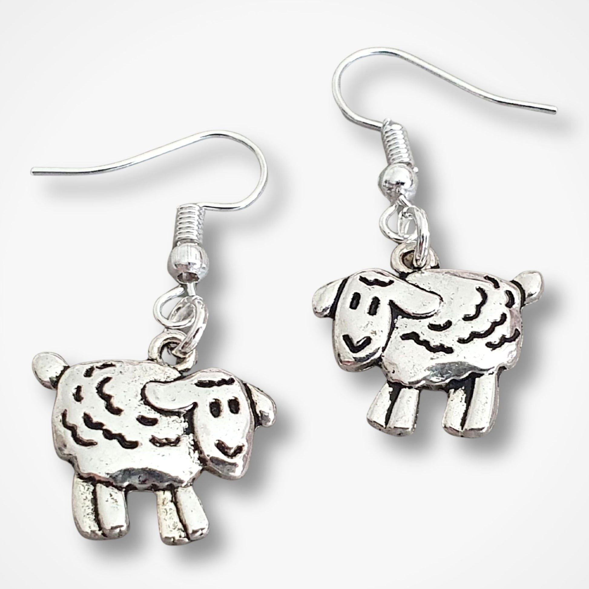 Silver sheep-shaped earrings on a white background