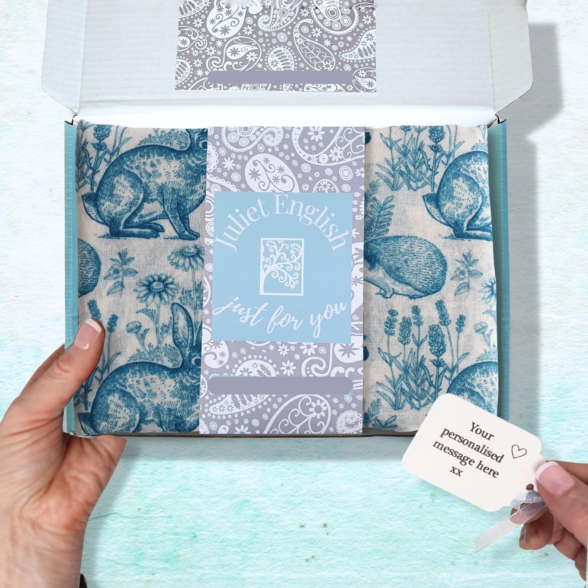 Packaged woodland animal scarf with a personalized message card on a light blue background