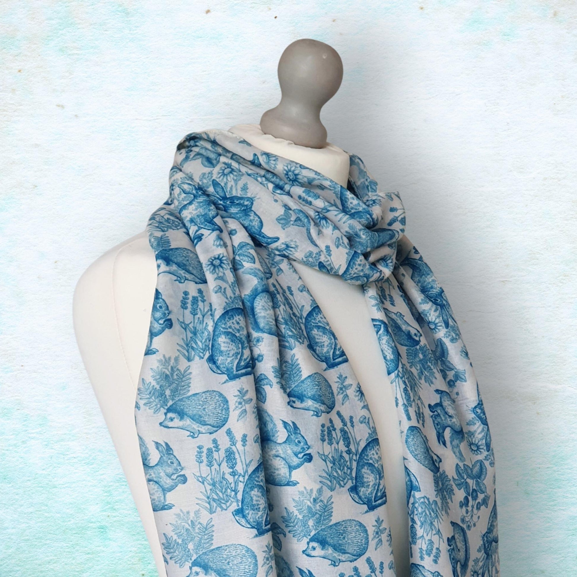Mannequin wearing a blue and white patterned scarf with animals on a light blue background