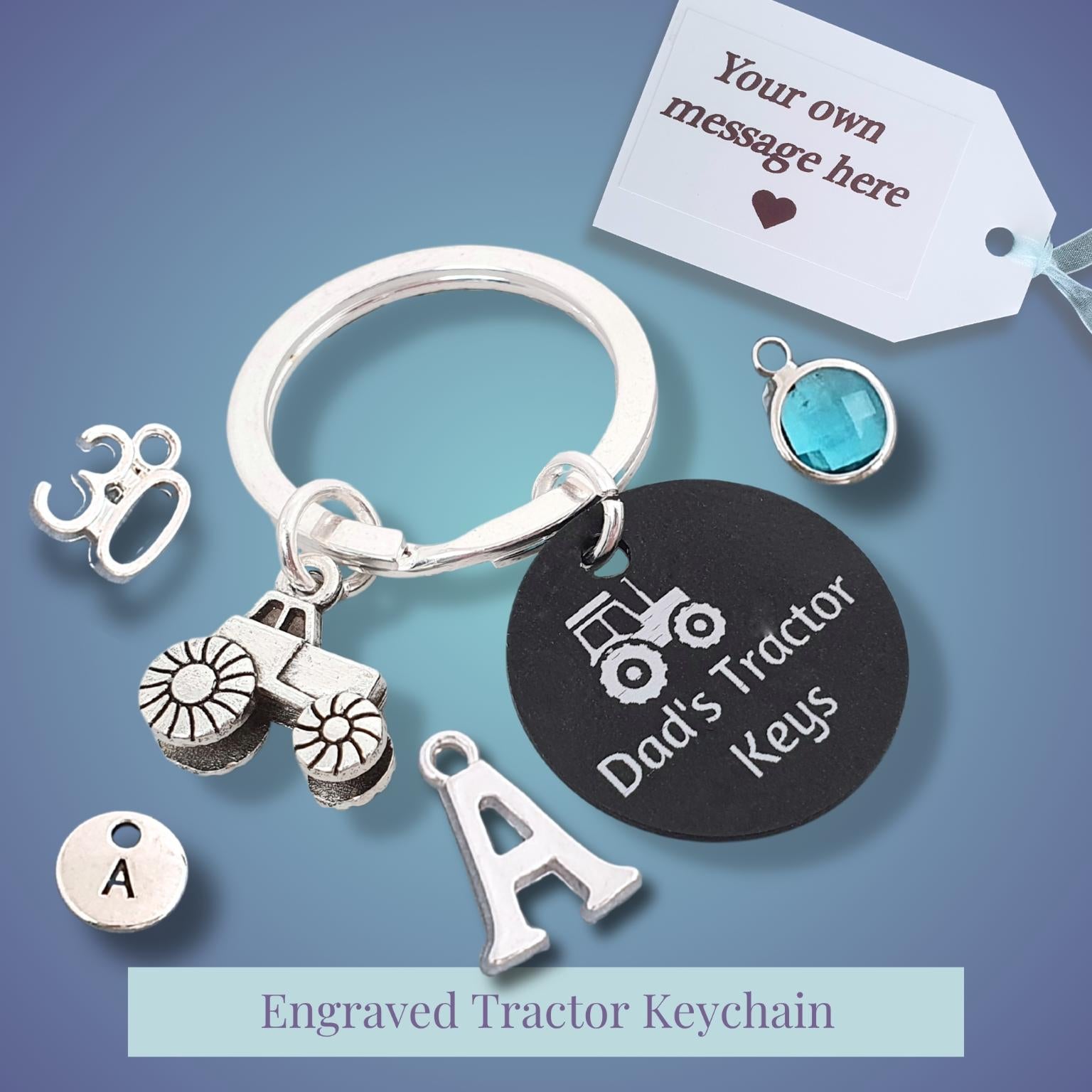 A customizable tractor keychain set on a blue gradient background, featuring a silver-tone split ring, a black circular tag engraved with 'Dad's Tractor Keys', various tractor and letter charms, and a white gift tag with a message field.