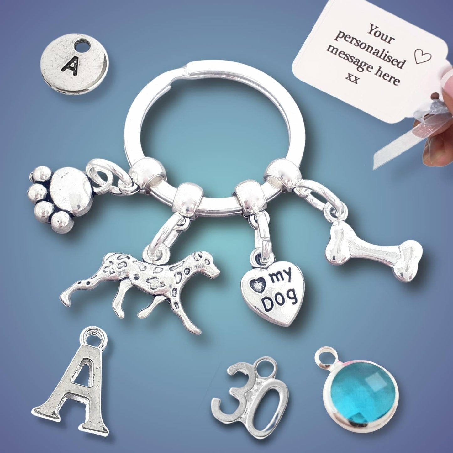 Silver keychain with various charms including a dog, paw print, and bone on a blue background.