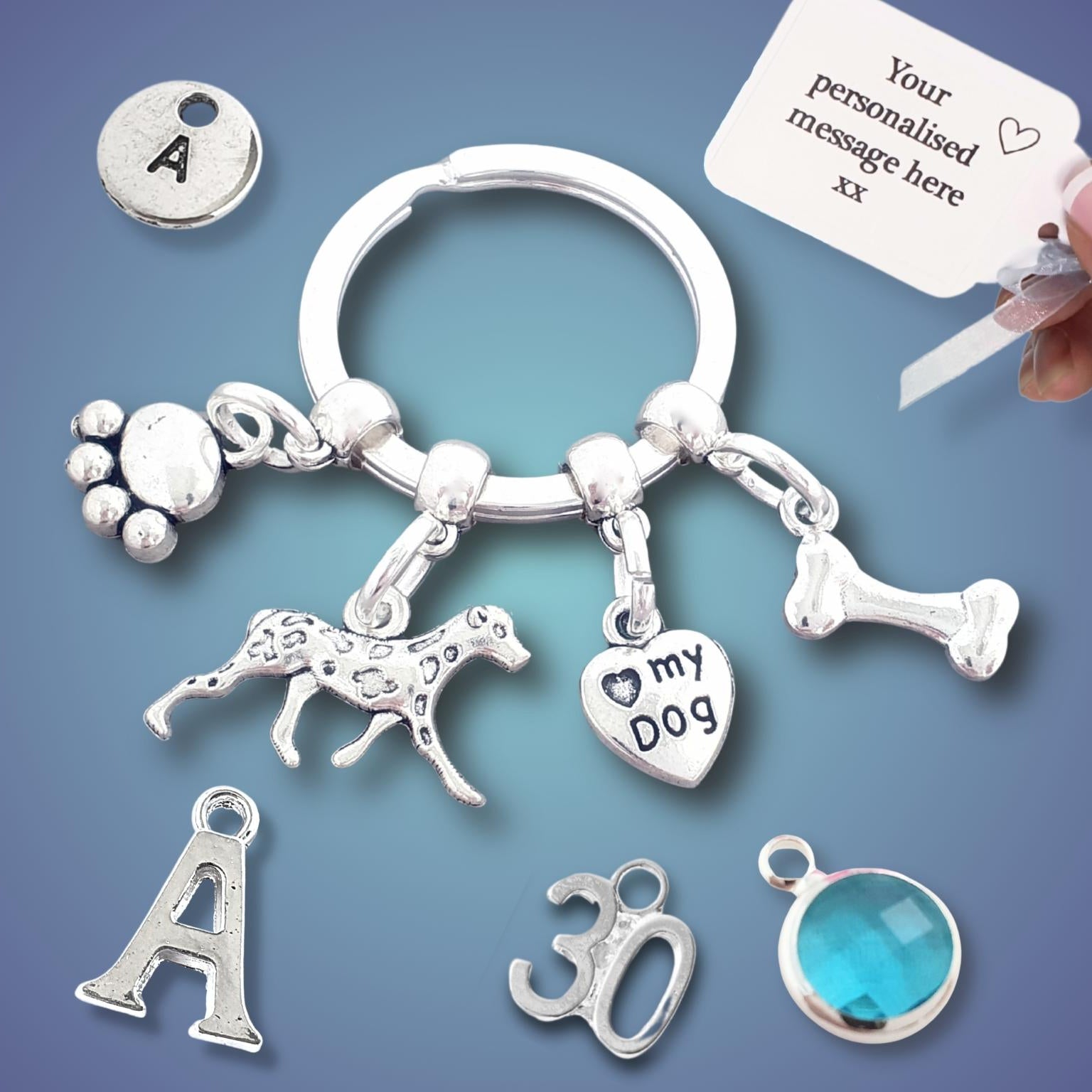Silver keychain with various charms including a dog, paw print, and bone on a blue background.