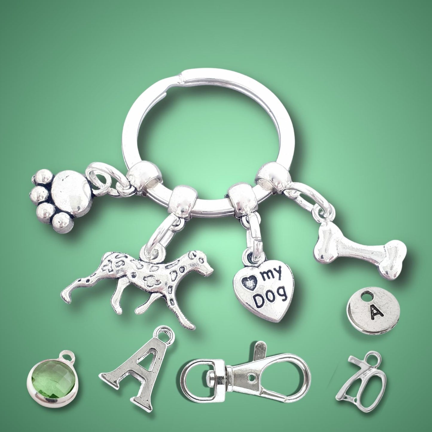 Keychain with paw, dalmatian, and bone charms on a green background