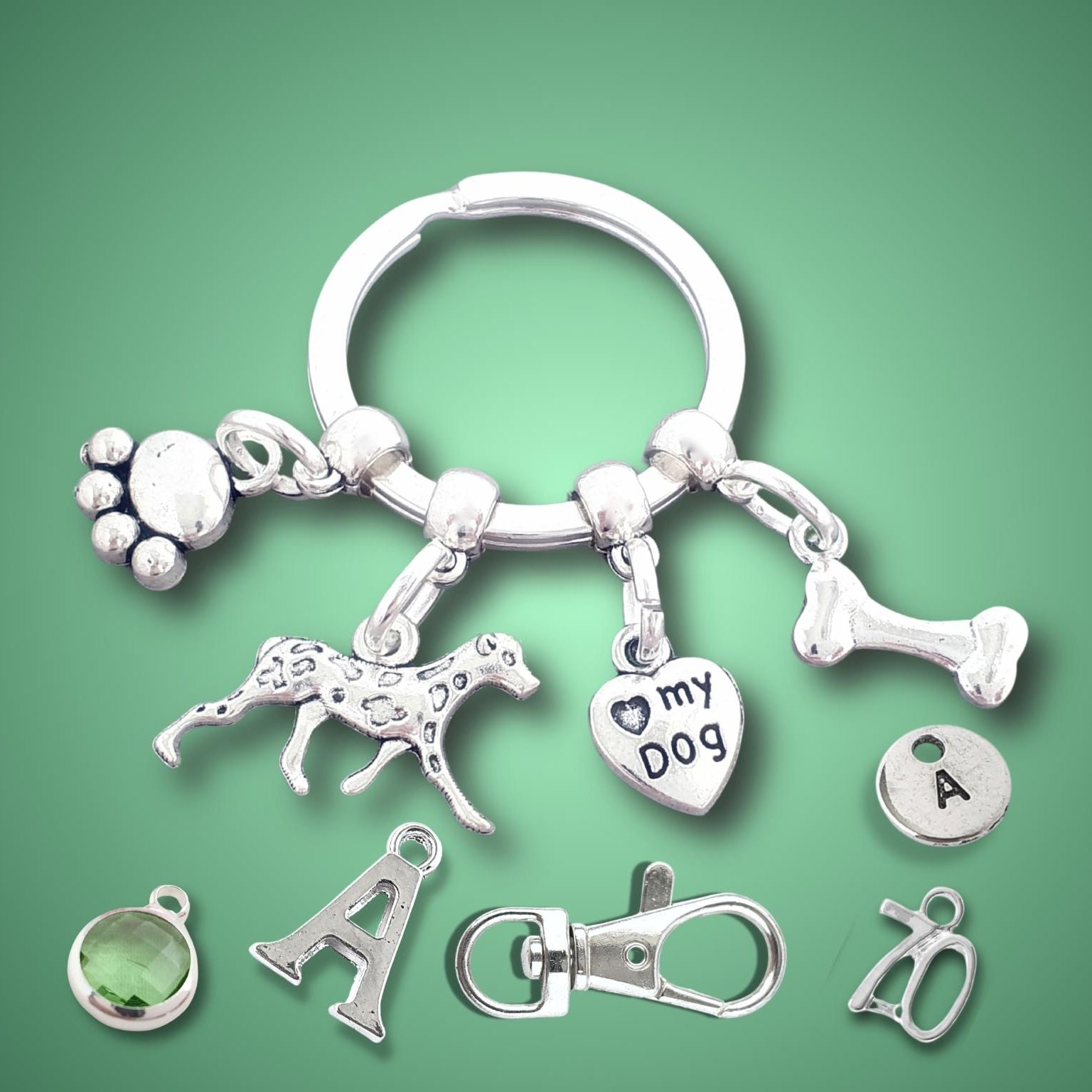 Keychain with paw, dalmatian, and bone charms on a green background