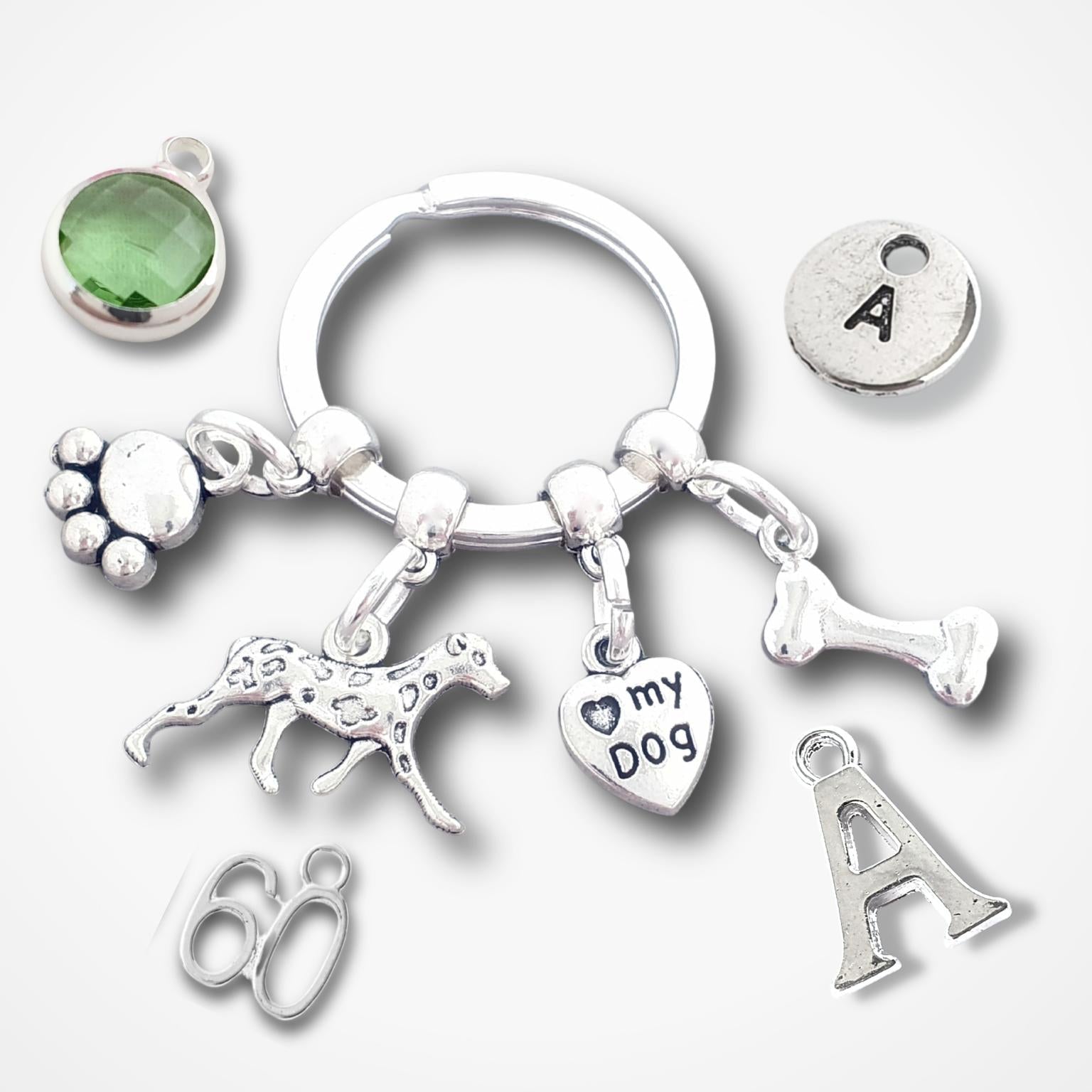 Silver keychain with various charms including a paw print, dog illustration, '60', 'I love my dog', and letter 'A' on a white background.