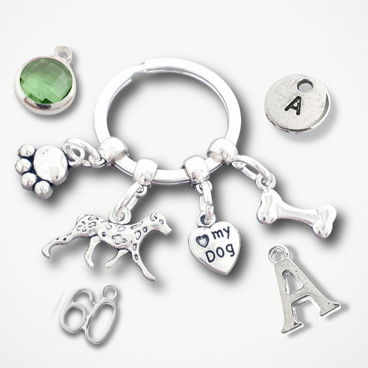 Silver keychain with various charms including a paw print, dog illustration, '60', 'I love my dog', and letter 'A' on a white background.