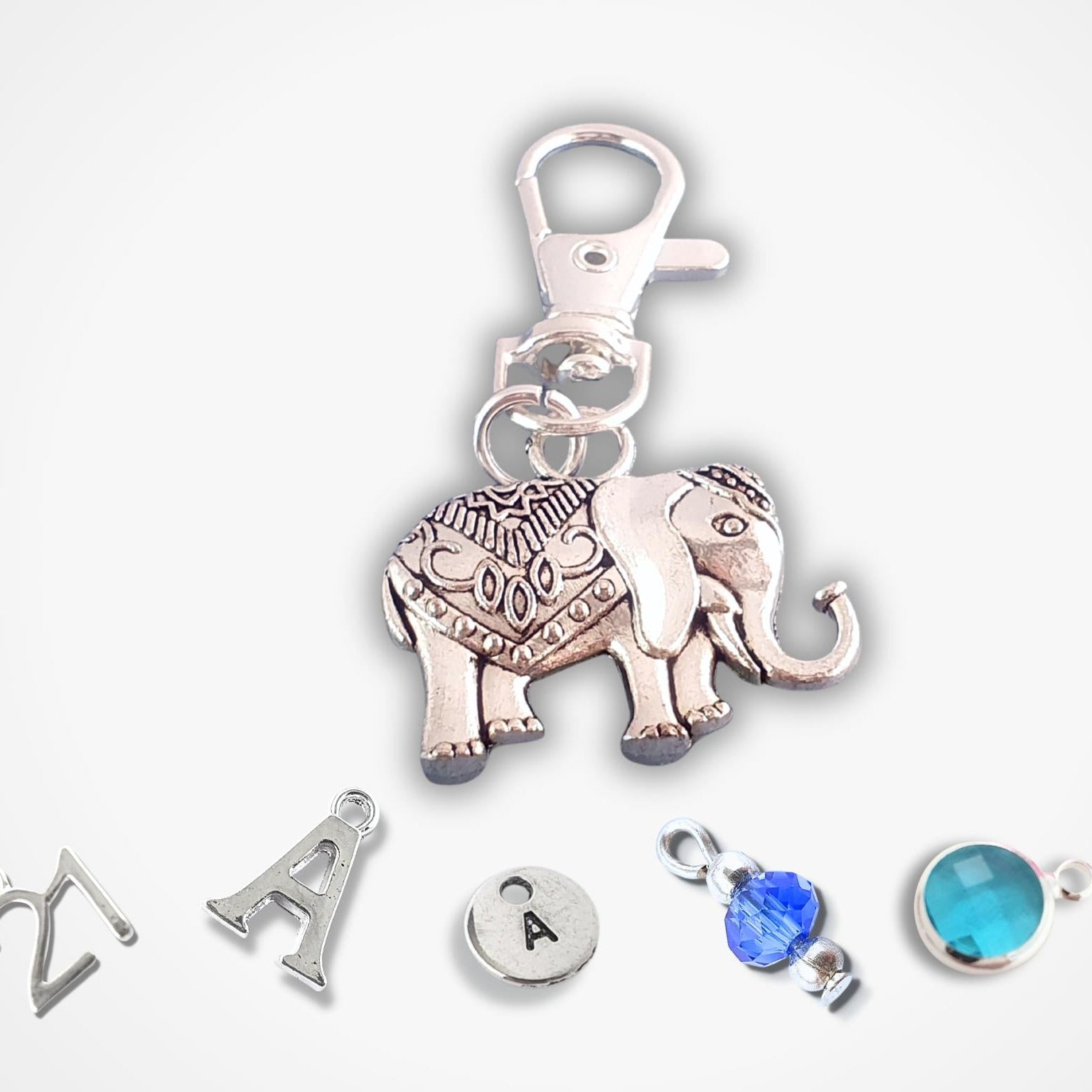Silver elephant charm with blue gemstones on a white background