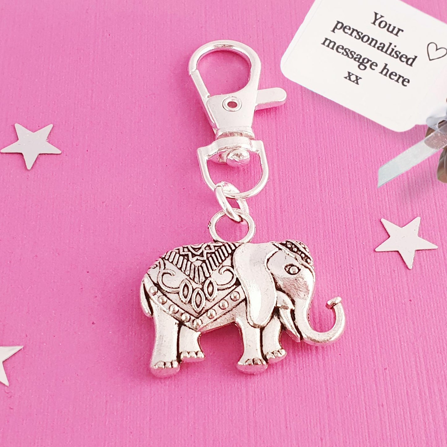 Silver elephant keychain with a pink background