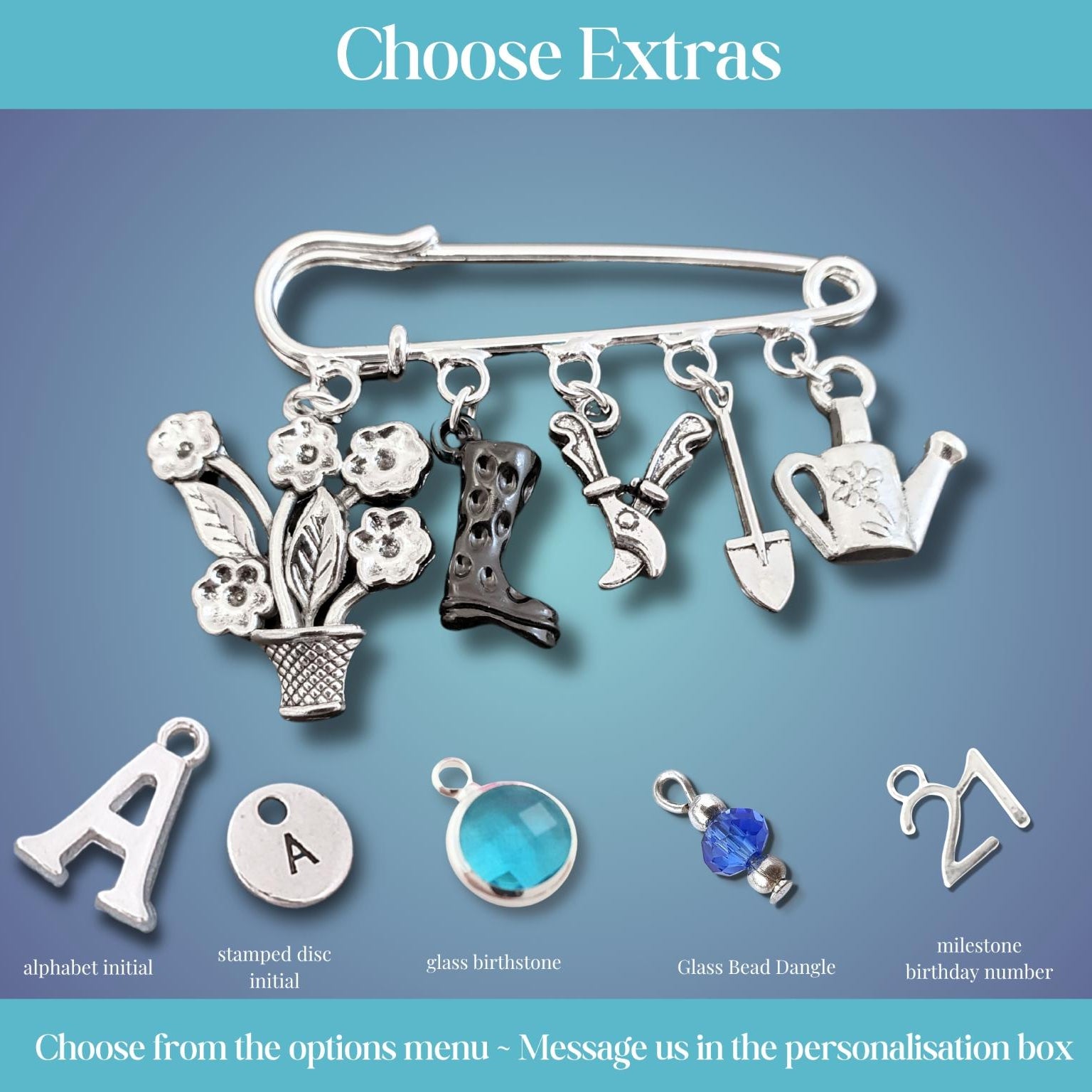 A product customization graphic showing a silver safety pin charm set with gardening-themed charms (flowers, boots, gardening tools, watering can) and options for personalization including alphabet initial, stamped disc, glass heart dangle, and milestone birthday number on a blue gradient background.