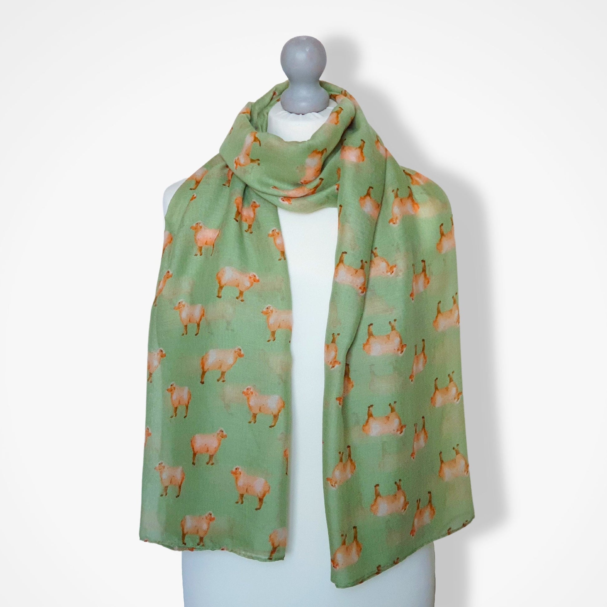 Green scarf with sheep pattern on a mannequin against a white background