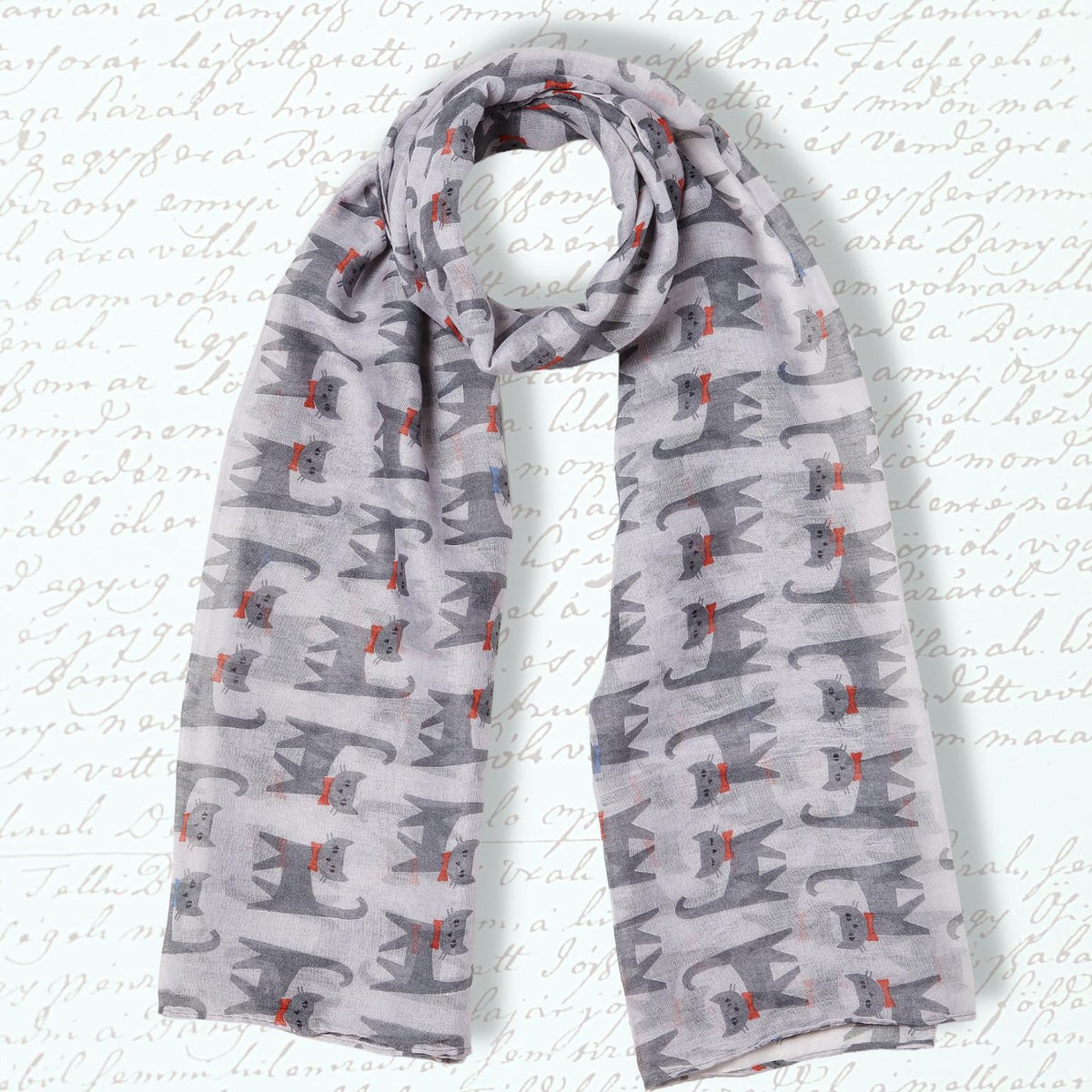 A lightweight gray scarf with a repeating pattern of stylized gray cats and small red bows, displayed against a white background with faint cursive script.