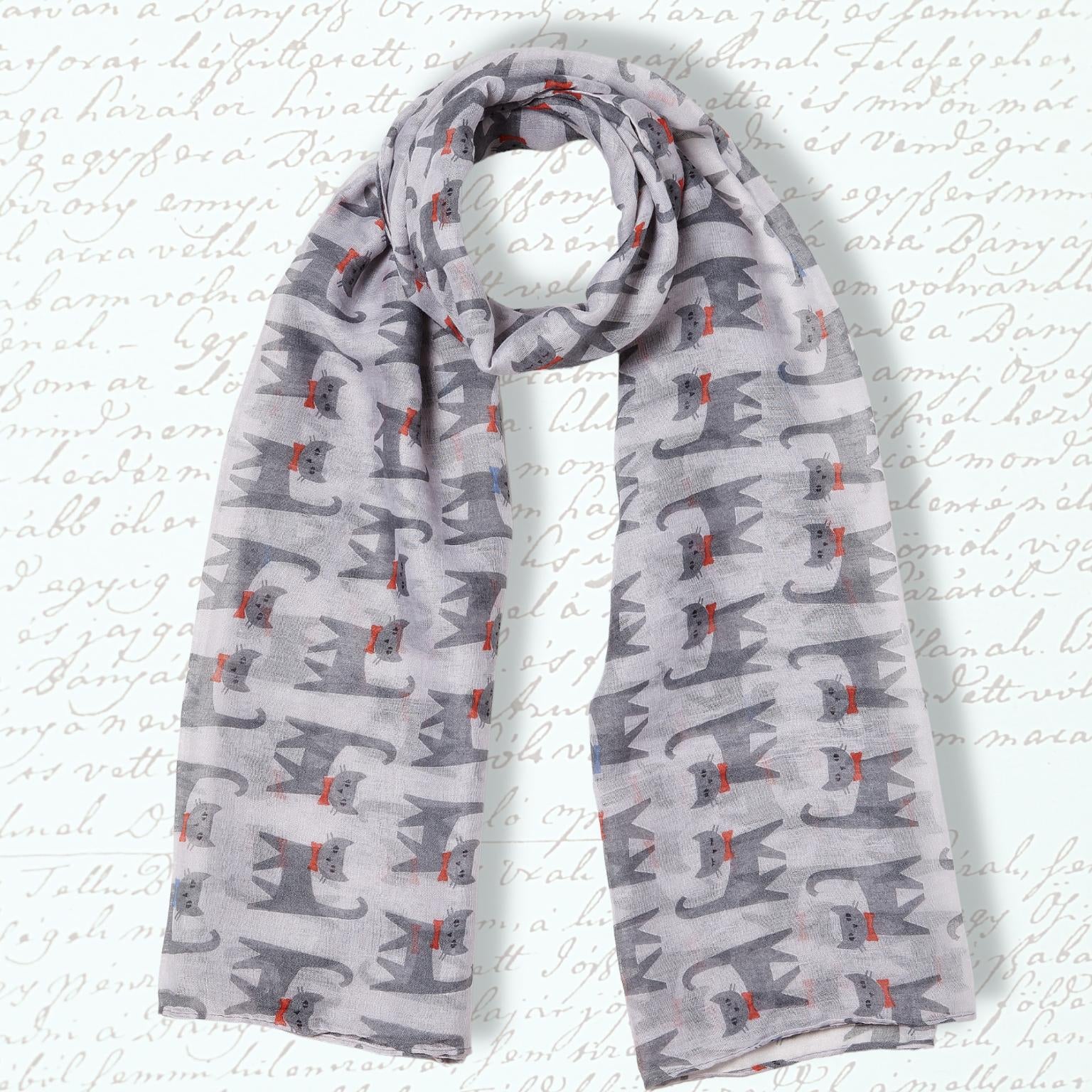 A lightweight gray scarf with a repeating pattern of stylized gray cats and small red bows, displayed against a white background with faint cursive script.